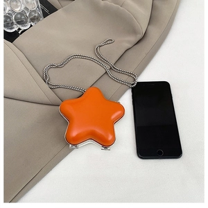 Detailed size comparison of the orange star-shaped mini bag with a smartphone and silver chain