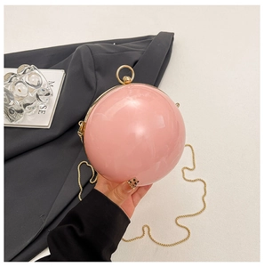 Detail of pink spherical acrylic evening bag with gold ring handle and chain strap