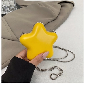 Detail of yellow star-shaped mini bag with metallic chain held in hand for scale