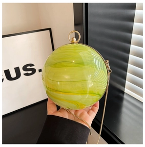 Detail of green marble acrylic spherical clutch bag with golden metal ring handle