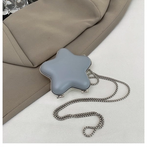 Macro view of blue star-shaped mini lipstick bag with silver metal chain on a blazer