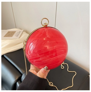 Detail of red marble acrylic sphere evening bag with gold ring handle and chain strap