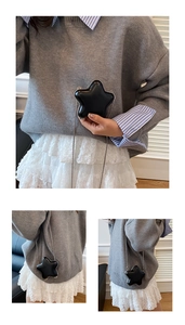 Close-up of black star-shaped crossbody bag with silver chain strap on grey sweater