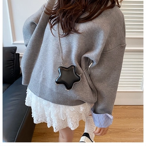 Star-shaped black mini crossbody bag with silver chain strap worn by a female model
