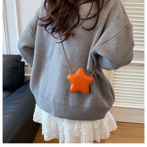 Mini orange star-shaped crossbody bag with silver chain strap shown on model outfit