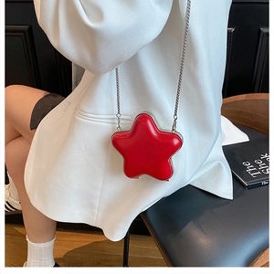 Close-up of red star-shaped crossbody bag with silver chain strap on model