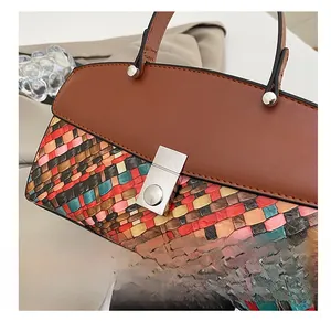 Macro view of silver buckle on woven handbag with brown leather flap and multi-color fabric