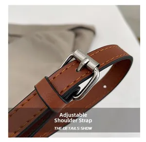 Detail of adjustable brown leather shoulder strap with silver buckle and orange stitching