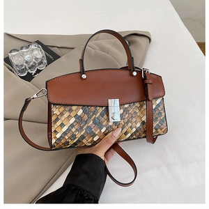 Détail du sac cabas tissé avec rabat en cuir marron et boucle argentée sur blazer beige