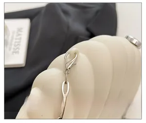 Detail of silver lobster clasp and metal chain on ivory acrylic shell bag with wave texture