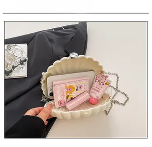 Interior capacity detail showing ivory shell bag holding a phone, wallet, and cosmetics