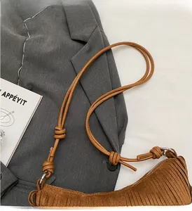 Detail of brown suede crescent bag with long fringe tassels and knotted leather strap