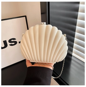 Macro view of shell-shaped acrylic clutch with ribbed texture and gold chain strap