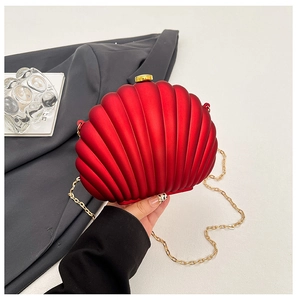 Close-up of a matte red shell-shaped evening bag with golden metal clasp and chain