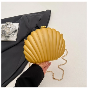 Detail of yellow shell-shaped acrylic evening bag with gold chain strap and metal clasp