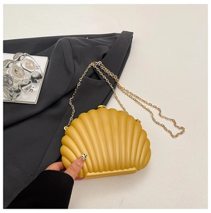 Detailed close-up of yellow shell-shaped acrylic evening bag with gold chain strap