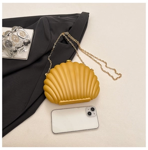 Yellow shell clutch bag with gold chain strap shown next to a smartphone for scale
