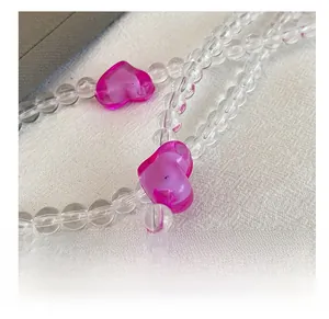 Close-up of clear acrylic beads and pink heart charms on a stylish crossbody bag