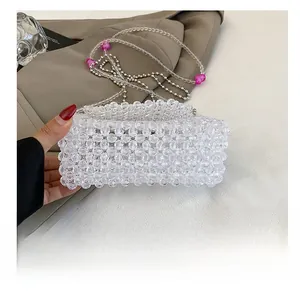 Detail of clear acrylic beaded bag featuring pink heart accents on the woven strap