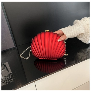Detail of red shell-shaped evening clutch with vertical texture and gold chain strap