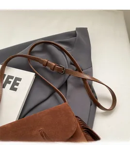 Détail de la longue bandoulière en cuir lisse et du sac à franges en daim marron
