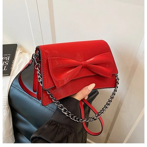 Dettaglio della borsa a tracolla in vernice rossa con un grande fiocco decorativo