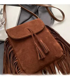 Détail du sac bandoulière en daim marron avec franges décoratives et mise en scène photo