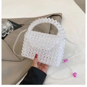 Close-up of a woven acrylic bead bag featuring pink heart charms and a transparent strap