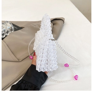 Close-up of woven clear acrylic beaded bag featuring pink heart charms and metallic clasp