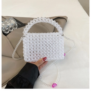 Detail of white acrylic beaded handbag featuring pink heart charms and woven texture