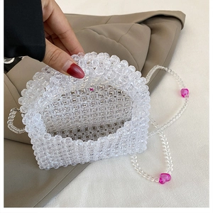 Detail of clear acrylic beaded bag featuring pink heart accents and woven texture
