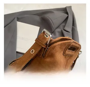 Close-up of adjustable shoulder strap with silver buckle on brown suede tassel bag
