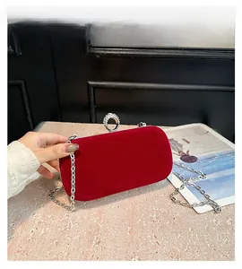 Detail of red velvet evening bag featuring luxury rhinestone ring clasp and silver chain