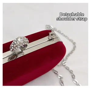 Detail of red velvet evening bag featuring detachable chain strap and rhinestone ring clasp