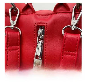 Détail de la fermeture éclair argentée et des attaches de sangle sur le sac à dos rouge