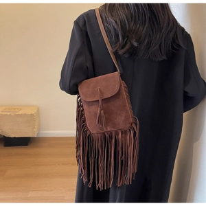 Gros plan d'un petit sac carré en daim marron avec des franges denses et des glands
