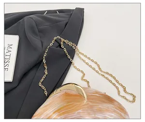 Detail of amber acrylic evening bag with textured finish and golden chain strap