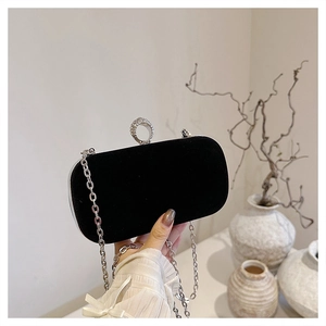 Detail of black velvet evening clutch featuring a rhinestone ring clasp and silver chain strap