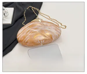 Detail view of marble pattern acrylic evening clutch with gold chain and phone for size