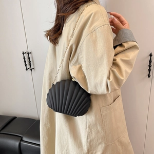 Fashionable black shell acrylic evening bag with gold chain strap worn by model