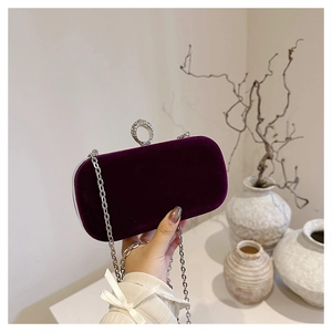 Macro detail of wine red velvet evening bag with sparkling crystal ring clasp and silver chain