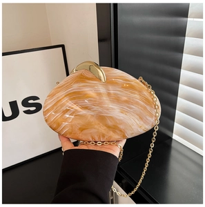 Close-up of shell-shaped acrylic evening bag with amber marble pattern and gold chain