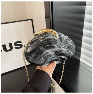Detail of marble pattern acrylic evening bag with gold metal clasp and chain strap