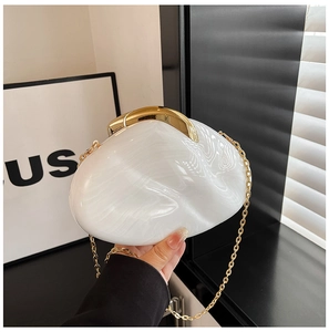 Detailed close-up of white marble acrylic clutch with gold clasp and chain strap