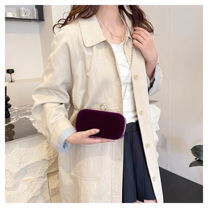Model wearing a deep purple velvet clutch bag with diamond-studded ring clasp and silver chain