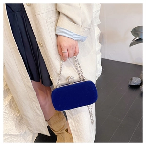 Close-up of deep blue velvet evening clutch with silver chain and rhinestone lock