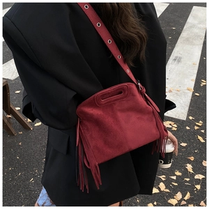 Detail of burgundy fringe crossbody bag with metallic grommets on shoulder strap