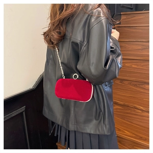 Detail of red velvet clutch bag with silver chain and crystal round lock on a model