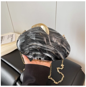 Detail of evening clutch with marble pattern, gold clasp and elegant chain strap