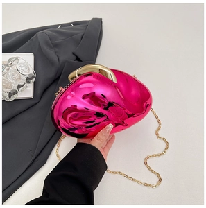 Detail of rose pink metallic acrylic clutch with gold hardware on a grey blazer suit